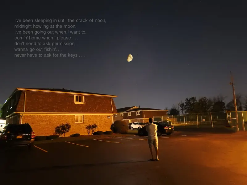 Aldo looking up at the moon over a parking lot at night